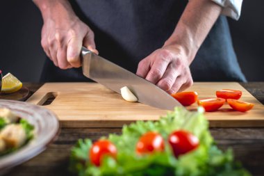 Şef sarımsağı kesiyor. İştah açıcı lezzetli bir yemek pişirme süreci kavramı