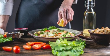 Şef salata sosu için limon sıkıyor. Yemek pişirme süreci kavramı çok lezzetlidir.
