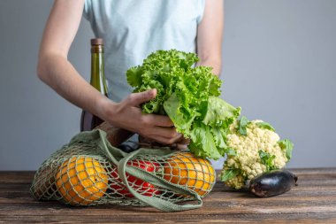Modern bir kadın alışveriş paketlerini açıyor, ürünleri torbadan çıkarıyor. Çevre dostu davranış anlayışı, yeniden kullanılabilir çantaların kullanımı ve çevre kaygısı