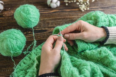 Kadın iğnelerle sıcacık bir kazak örüyor. Hobi kavramı ve el yapımı şeyler yaratmak..
