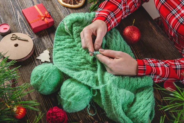 女性はプレゼントとして暖かい居心地の良いセーターを編んでいます お正月やクリスマスに手作りの贈り物を作るというコンセプト — ストック写真