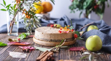 Sonbahar yaprakları ve böğürtlenlerle süslenmiş kahverengi kremalı pasta. Ahşap arka plan. Sonbahar havası ve atmosferi kavramı.