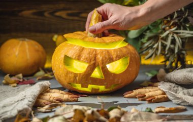 El, yüzü kesilmiş bir şekilde balkabağını açıyor. Cadılar Bayramı 'nı ve gizemli ve korkutucu bir atmosferi kutluyoruz..