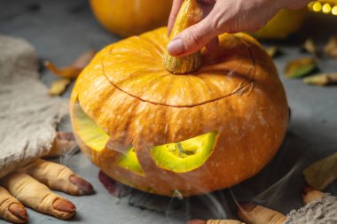 El, yüzü kesilmiş bir şekilde balkabağını açıyor. Cadılar Bayramı 'nı ve gizemli ve korkutucu bir atmosferi kutluyoruz..