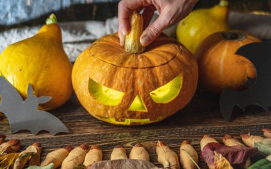 El, yüzü kesilmiş bir şekilde balkabağını açıyor. Cadılar Bayramı 'nı ve gizemli ve korkutucu bir atmosferi kutluyoruz..