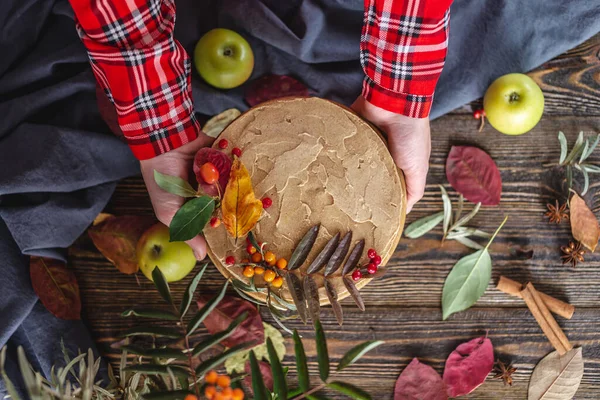 女性の手には 秋の葉や果実で飾られたムースブラウンのケーキを持っています 秋の雰囲気と気分の概念 — ストック写真