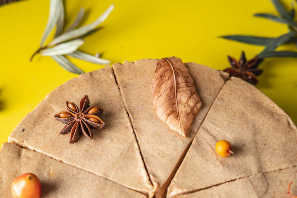 Brown mousse cake minimally decorated with autumn symbols on a yellow background. Concept of seasons and autumn mood.