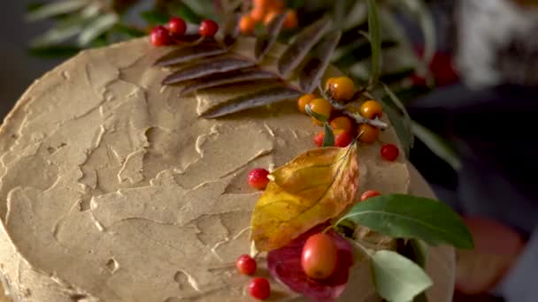 用秋天的叶子和浆果装饰的棕色慕斯蛋糕正在一个木制看台上旋转。秋天的气氛和心情概念 — 图库视频影像