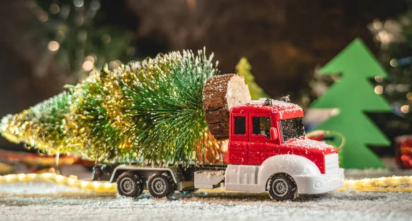 Een Rood Witte Speelgoedauto Vervoert Een Kerstboom Tegen Een Achtergrond — Stockfoto