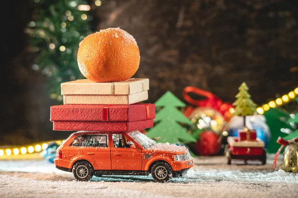 Een Oranje Speelgoedauto Rijdt Langs Een Besneeuwde Weg Tegen Achtergrond — Stockfoto