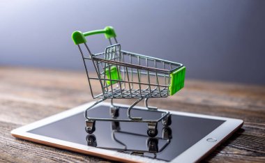 Küçük alışveriş arabası ve tablet. Konforlu evinizden gelen mallarla internetten mal satın alma kavramı.