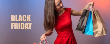 Kırmızı elbiseli genç kadın elinde kağıt alışveriş torbaları tutuyor. Kara Cuma kelimeleri onun yanında yazılı. Alışveriş ve satış kavramı.