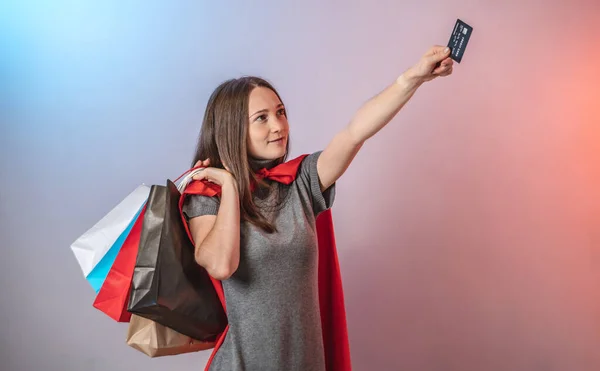 Młoda Zdeterminowana Kobieta Pelerynie Superbohatera Trzyma Torby Zakupy Kartę Kredytową — Zdjęcie stockowe