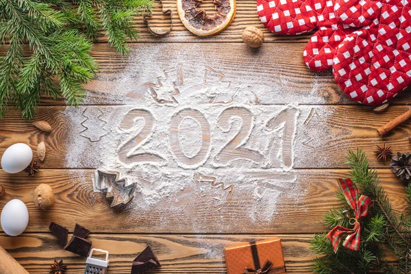 2021年の数字は 木製のテーブルに散らばっている小麦粉に書かれています 新年のコンセプトと休日のクッキーの調理 — ストック写真