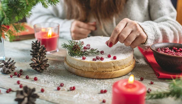 雪を模したココナッツフレークを散りばめた赤い果実と白いムースのお祝いケーキを飾る女性 クリスマスと新年のコンセプト — ストック写真