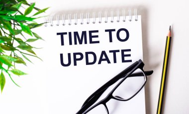 Güncelleme zamanı, bardakların, kalemlerin ve yeşilliklerin yanındaki beyaz bir masaya yazılmıştır. İş konsepti