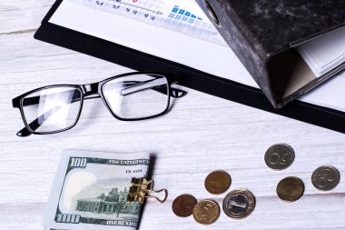 Gözlükler, hesap makinesi, para ve evraklar için bir klasör bir ışık masasında. İş konsepti