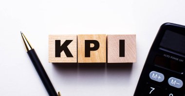 KPI, arka planda bir kalem ve hesap makinesi arasındaki tahta küplere yazılır. İş konsepti