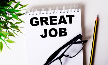 Yeşil bir bitkinin, siyah çerçeveli gözlüklerin ve siyah bir kalemin yanında beyaz bir deftere yazılmış güzel bir çalışma. İş konsepti