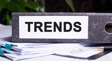 TRENDS kelimesi, belgelerin üstündeki gri belge klasörüne yazılmıştır. İş konsepti