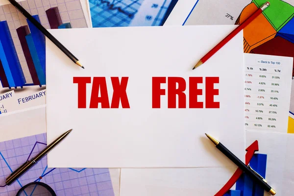 TAX FREE is written in red on a white sheet next to graphs, pens and pencils. Tax concept