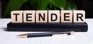 TENDER bir kalem ve not defterinin yanındaki tahta küplere yazılmıştır. İş konsepti