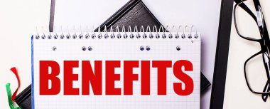 BENEFITS kelimesi siyah çerçeveli gözlüklerin yanındaki deftere kırmızı ile yazılmıştır.