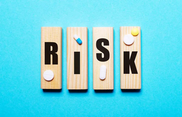 Słowo Risk Jest Napisane Drewnianych Blokach Niebieskim Tle Pobliżu Pigułek — Zdjęcie stockowe