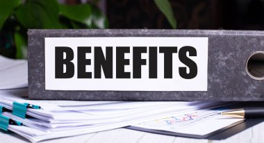 Belgelerde BENEFITS yazılı gri bir klasör var. İş konsepti