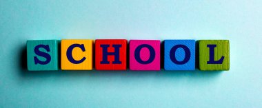 Mavi arka planda, ahşap çok renkli küplere yazılmış kelime okulu.