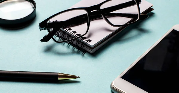 Een Blauwe Achtergrond Staan Een Pen Telefoon Bril Top Zicht — Stockfoto