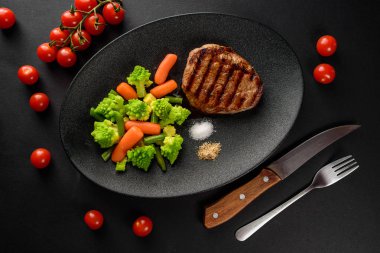 bir siyah plaka ve siyah masa sebzeli ızgara sığır eti biftek