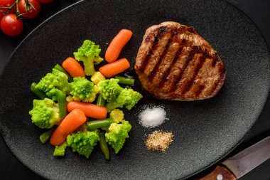 bir siyah plaka ve siyah masa sebzeli ızgara sığır eti biftek