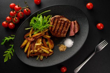 patates ile dana biftek siyah bir tabağa dilimlenmiş