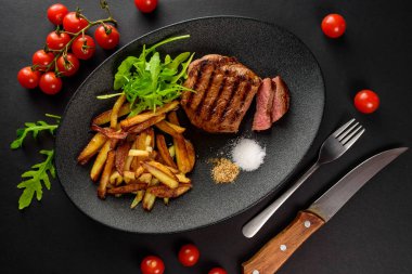 patates ile dana biftek siyah bir tabağa dilimlenmiş