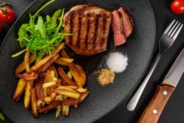 patates ile dana biftek siyah bir tabağa dilimlenmiş