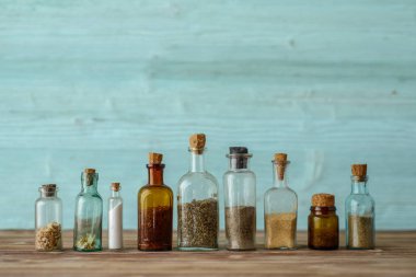 Ahşap arka plan üzerinde çeşniler ile küçük eski cam kavanoz