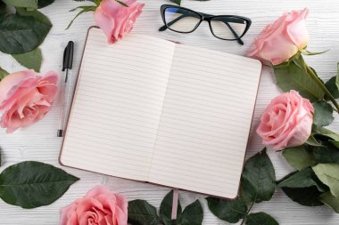 Gül bir beyaz tahta masada boş not defteri