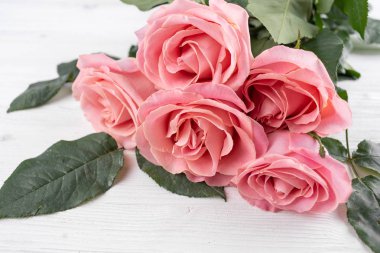 bir beyaz tahta masada beş pembe Gül yalan