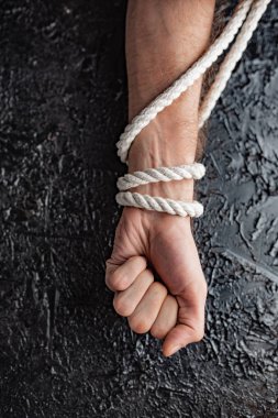 siyah bir arka planda bir ip ile bağlanmış bir el şeklinde kısıtlama ve bağımlılığı sembolizm