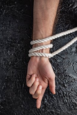 siyah bir arka planda bir ip ile bağlanmış bir el şeklinde kısıtlama ve bağımlılığı sembolizm