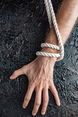 siyah bir arka planda bir ip ile bağlanmış bir el şeklinde kısıtlama ve bağımlılığı sembolizm