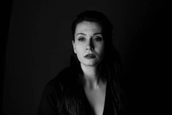 Portrait of a girl in black and white on black background in noir style