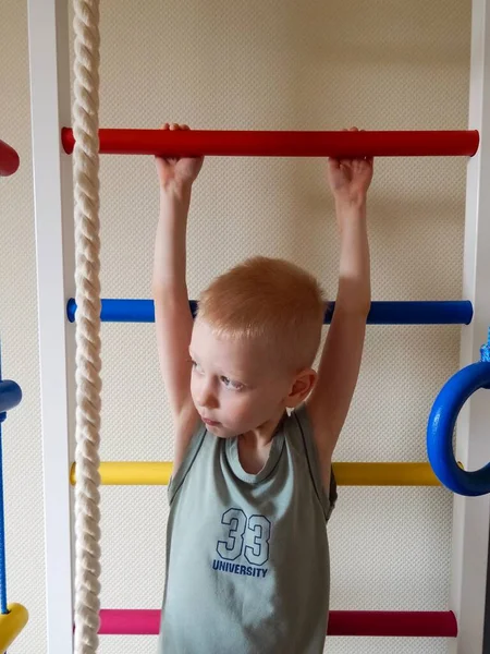 boy goes in for sports on a ladder, home work out