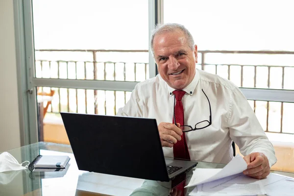 Efendim deftere Corona virüsü salgını sırasında ev ofis sistemi üzerinde çalışıyor. Beyefendi evde gömlek ve kravat takıp maskesiyle çalışıyor.