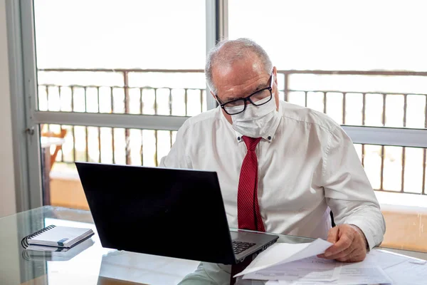 Efendim deftere Corona virüsü salgını sırasında ev ofis sistemi üzerinde çalışıyor. Beyefendi evde gömlek ve kravat takıp maske takarak çalışıyor.