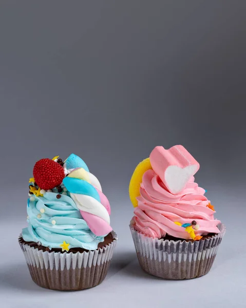 Marshmallow aksanlı mavi ve pembe renkli kekler. Beyaz ve gri bir arka planda izole edilmiş. Boşluğu kopyala
