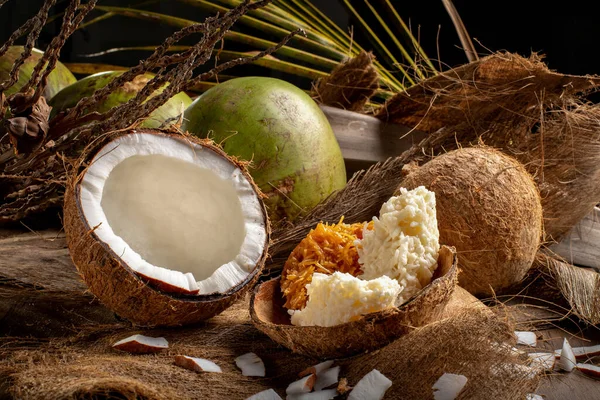 开放的绿色椰子和成熟的椰子 配上甜椰子 巴西甜椰子 木制背景和干椰叶 — 图库照片