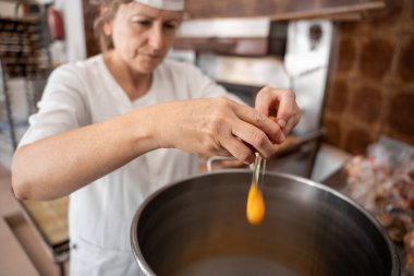 Fırıncı kadın büyük bir tavaya yumurta ekliyor.