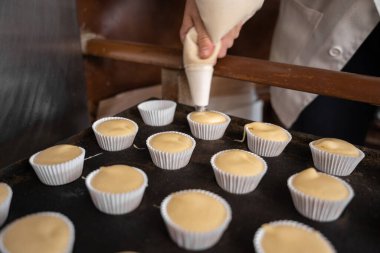 Kekleri hazırlamak için hamur işini hamur torbasıyla kalıba döken tanınmamış bir fırıncı.